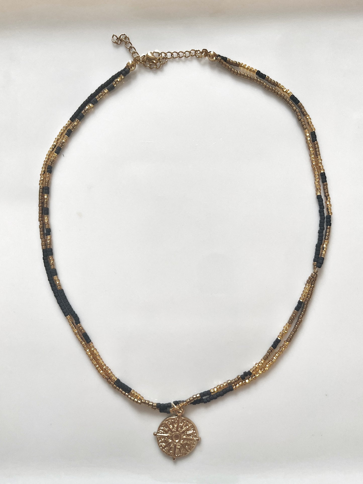 Collier en perle de verre et pendentif au style ethnique en acier inoxydable.